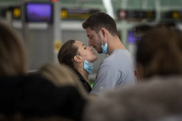 A couple kiss,  at the Barcelona airport, Spain, Thursday, March 12, 2020. President Donald Trump, who had downplayed the coronavirus for weeks, suddenly struck a different tone, announcing strict rules on restricting travel from much of Europe to begin this weekend. For most people, the new coronavirus causes only mild or moderate symptoms, such as fever and cough. For some, especially older adults and people with existing health problems, it can cause more severe illness, including pneumonia. (Photo by Emilio Morenatti/AP Photo)