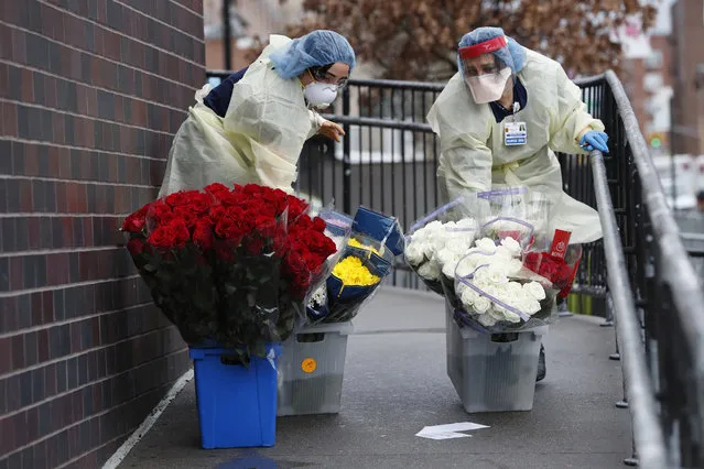 Emergency room nurses transport buckets of donated flowers up a ramp outside Elmhurst Hospital Center's emergency room, Saturday, March 28, 2020, in New York. The hospital has been heavily taxed by treating an influx of coronavirus patients during the current viral pandemic. Currently, New York leads the nation in the number of cases, according to Johns Hopkins University, which is keeping a running tally. (Photo by Kathy Willens/AP Photo)