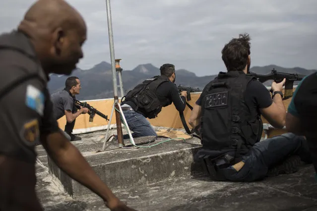 In this July 7, 2016 photo, police exchange gunfire with drug traffickers at the “pacified” Alemao slum complex in Rio de Janeiro, Brazil. Half a dozen officers had entrenched themselves behind a cable car station while they shot it out with suspected drug traffickers in the sprawling cluster of slums in north Rio. Shootouts erupt daily, even in slums where community policing programs had successfully rewritten the narrative in recent years. (Photo by Felipe Dana/AP Photo)