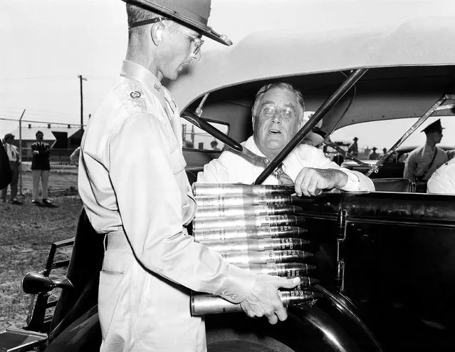 President Franklin D. Roosevelt, on a personal tour to inspect results of the nation's expanded defense program, is looking over a clip of 37 mm. anti-aircraft shells at Langley Field in Hampton, Va., on July 29, 1940, where he stopped on his tour of defense bases. Holding the clip is Lieut. E.H. Waters. (Photo by AP Photo)