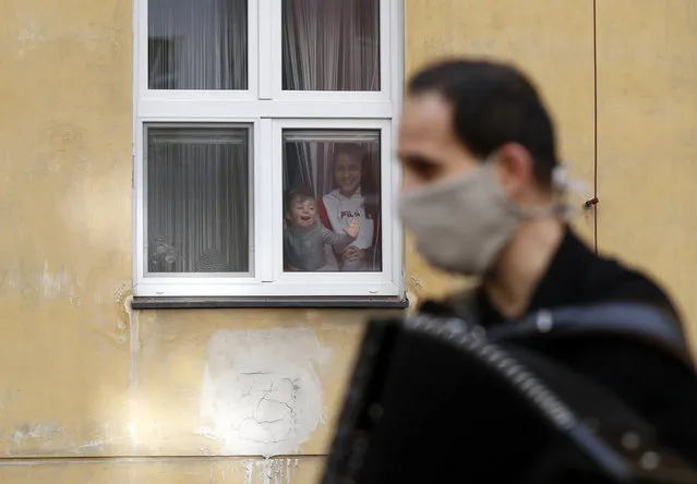 A member of the artistic group Cirk La Putyka performs on a accordion to entertain residents as the movement remains restricted in affords to stem the spread of the novel coronavirus called COVID-19 in Prague, Czech Republic, Tuesday, April 14, 2020. (Photo by Petr David Josek/AP Photo)
