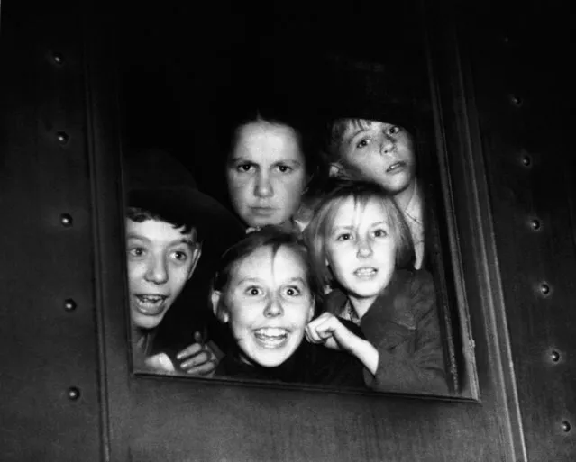 British children, whose parents are employees of Kodak Limited, the English affiliate of the Eastman Kodak Company, crowd a railroad car window as they arrive in Rochester, New York on August 24, 1940, to live in the homes of Kodak employees there for the duration of the war. (Photo by AP Photo)