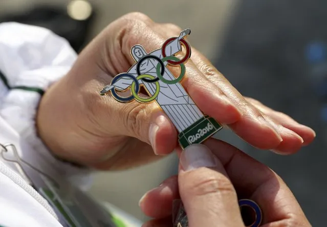 A pin trader shows a Christ the Redeemer Olympic pin ahead of the 2016 Rio Olympics in Rio de Janeiro August 4, 2016. (Photo by Kai Pfaffenbach/Reuters)
