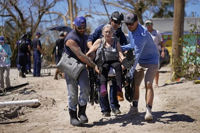 Rescuers help evacuate Suzanne Tomlinson, a resident who rode out the storm, as they carry her to a waiting boat in the aftermath of Hurricane Ian on Pine Island in Florida's Lee County, Sunday, October 2, 2022. The only bridge to the island is heavily damaged so it can only be reached by boat or air. (Photo by Gerald Herbert/AP Photo)