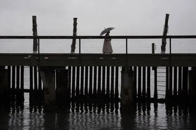 A pedestrian walks across a footbridge on the Halifax waterfront as rain falls ahead of Hurricane Fiona making landfall in Halifax on Friday, September 23, 2022. (Photo by Darren Calabrese/The Canadian Press via AP Photo)