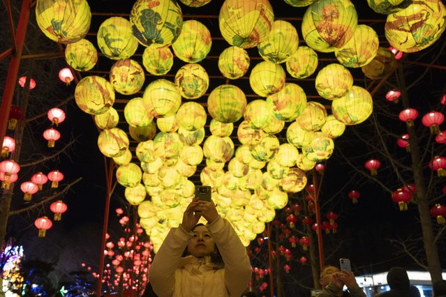 A woman takes photos near lanterns at the Lantern Festival during Yuanxiao, the fifteen day of the Lunar New Year in Beijing, Wednesday, February 12, 2025. (Photo by Ng Han Guan/AP Photo)