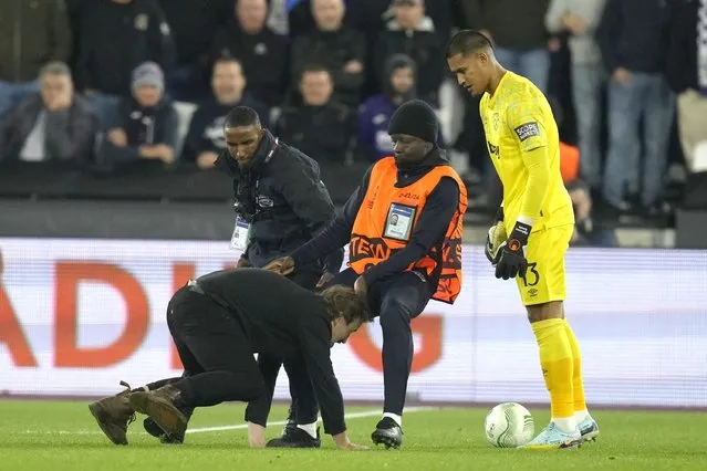 West Ham's goalkeeper Alphonse Areola looks on as stewards catch a pitch invader during the Europa Conference League Group B soccer match between West Ham United and Anderlecht at the London stadium in London, Thursday, October 13, 2022. (Photo by Kirsty Wigglesworth/AP Photo)