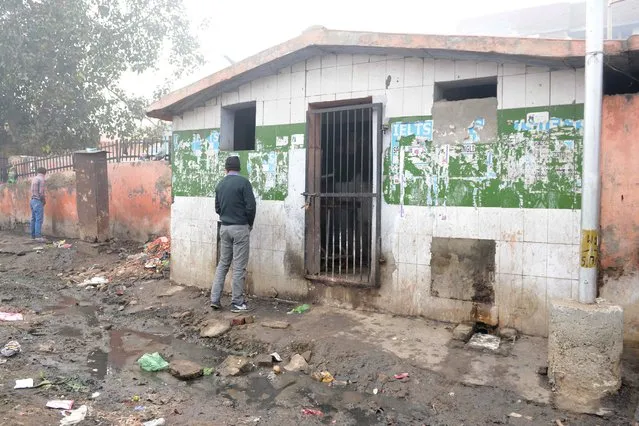 Indian men urinate outside of a locked public toilet on a street in Amritsar on November 12, 2017. (Photo by Narinder Nanu/AFP Photo)