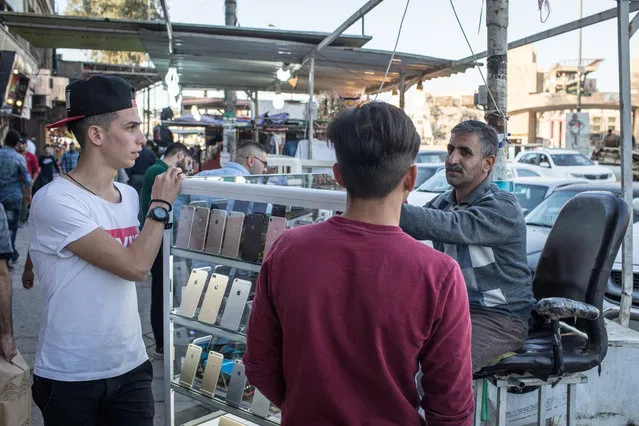 A man selling Iphones talks to customers at his street store in East Mosul on November 5, 2017 in Mosul, Iraq. (Photo by Chris McGrath/Getty Images)