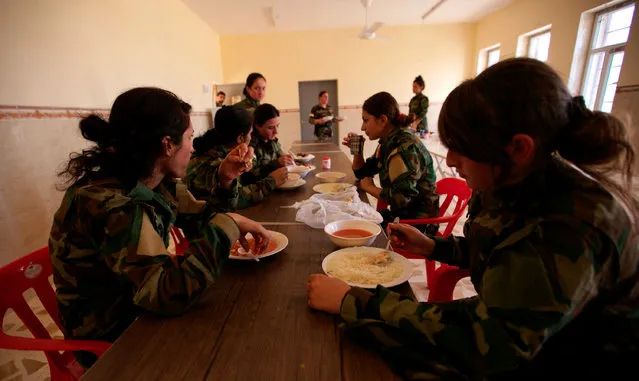 Yazidi females who have joined the Kurdish Peshmerga forces eat in Shingal, Iraq, August 24, 2016. (Photo by Ari Jalal/Reuters)
