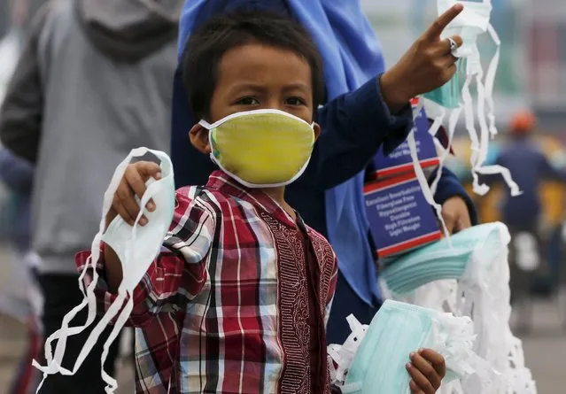 A child offers face masks to people along a haze shrouded street in Palembang, on the Indonesian island of Sumatra, September 20, 2015. (Photo by Reuters/Beawiharta)