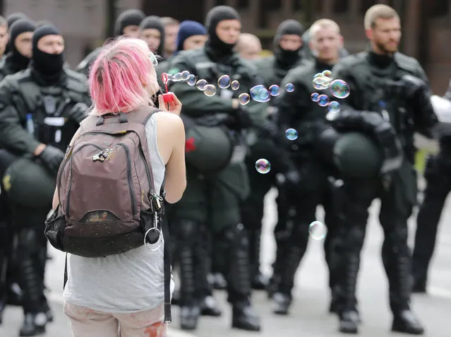 A protestor blows soap bubbles in front of riot police during a protest on the second day of the G-20 summit in Hamburg, northern Germany, Saturday, July 8, 2017, where the leaders of the group of 20 met for two days. (Photo by Michael Probst/AP Photo)