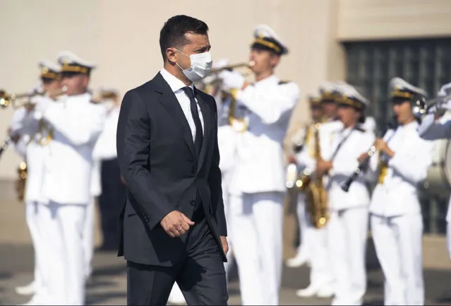 Ukrainian President Volodymyr Zelenskiy wearing a face mask to protect against coronavirus passes by a navy brass band to mark Ukraine's Navy Day in the Black Sea Port of Odesa, Ukraine, Sunday, July 5, 2020. (Photo by Ukrainian Presidential Press Office via AP Photo)