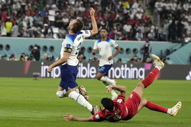 England's Harry Kane, left, is fouled by Iran's Morteza Pouraliganji during the World Cup group B soccer match between England and Iran at the Khalifa International Stadium, in Doha, Qatar, Monday, November 21, 2022. (Photo by Martin Meissner/AP Photo)