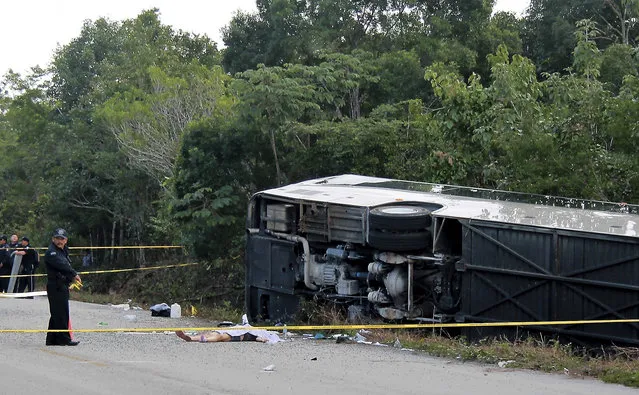The lifeless body of a passenger lies next to an overturned bus in Mahahual, Quintana Roo state, Mexico, Tuesday, December 19, 2017. The bus carrying cruise ship passengers to the Mayan ruins at Chacchoben in eastern Mexico flipped over on the highway early Tuesday. (Photo by Novedades de Quintana Roo via AP Photo)