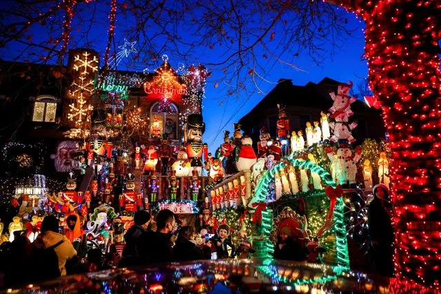 Tourists look at a house decorated with Christmas lights in the Dyker Heights neighborhood, Wednesday, December 21, 2022, in the Brooklyn borough of New York. (Photo by Julia Nikhinson/AP Photo)
