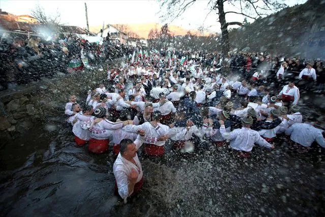 Men sing and dance in the waters of Tundzha river during a celebration of Epiphany Day in the town of Kalofer, Bulgaria on January 6, 2023. (Photo by Stoyan Nenov/Reuters)