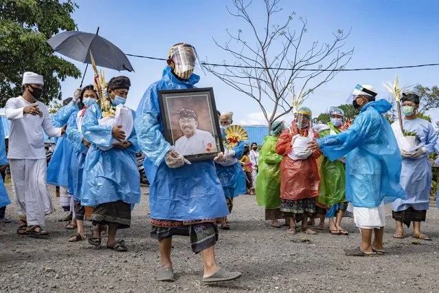 Balinese people wear protective suits during a Hindu cremation ceremony called “Ngaben” in Klungkung, Bali, Indonesia, 21 August 2020. The local government implemented a health protocol on every religious ritual activity involving several people in an attempt to curb the spread COVID-19. Bali has reopened to domestic tourism but the government is still evaluating options regarding international travellers. (Photo by Made Nagi/EPA/EFE)