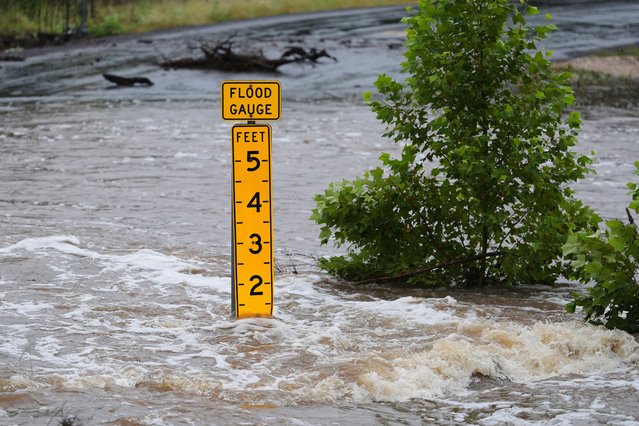 A flood gauge marks the height of water flowing over a farm-to-market road near Kerrville, Texas, on Friday, July 4, 2025. (Photo by Eric Gay/AP Photo)