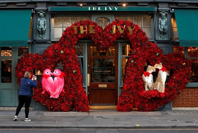 A woman photographs a Valentines Day floral display attached to the facade of a restaurant in London, Britain on February 13, 2023. (Photo by Peter Nicholls/Reuters)