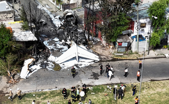 A drone view shows people standing at the site of the wreckage of a Challenger 300 aircraft that crashed near the San Fernando airport, on the outskirts of Buenos Aires, Argentina, on December 18, 2024. (Photo by Miguel Lo Bianco/Reuters)