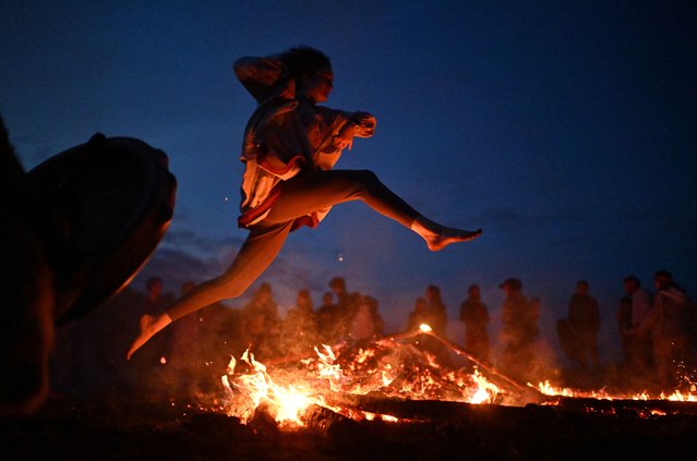 A woman jumps over a fire during the celebration of the summer solstice at a festival in the village of Okunevo in Omsk region, Russia on June 22, 2025. (Photo by Alexey Malgavko/Reuters)