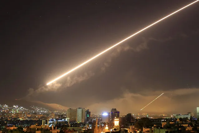 Damascus skies erupt with surface to air missile fire as the U.S. launches an attack on Syria targeting different parts of the Syrian capital Damascus, Syria, early Saturday, April 14, 2018. Syria's capital has been rocked by loud explosions that lit up the sky with heavy smoke as U.S. President Donald Trump announced airstrikes in retaliation for the country's alleged use of chemical weapons. (Photo by Hassan Ammar/AP Photo)