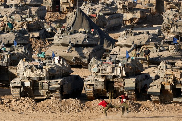 Israeli soldiers play soccer near tanks and armoured personnel carrier (APC), amid the ongoing conflict between Israel and the Palestinian Islamist group Hamas, near the Israel-Gaza border, in Israel on June 2, 2024. (Photo by Amir Cohen/Reuters)