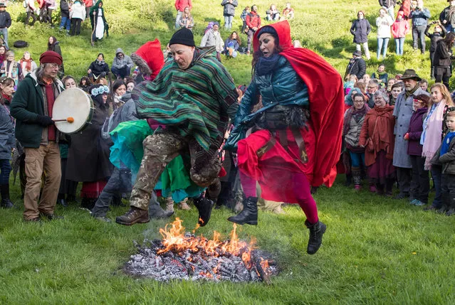 People jump over a fire as they gather in the Chalice Well Trust Gardens below Glastonbury Tor for a sun rise ceremony as they celebrate Beltane on May 1, 2018 in Somerset, England. Although more synonymous with International Workers' Day, or Labour Day, May Day or Beltane is celebrated by druids and pagans as the beginning of summer and the chance to celebrate the coming of the season of warmth and light. Other traditional English May Day rites and celebrations include Morris dancing and the crowning of a May Queen with celebrations involving a Maypole. (Photo by Matt Cardy/Getty Images)