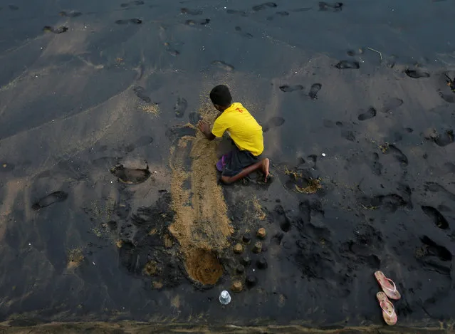 A boy digs sand on a dirty beach while playing in Colombo, Sri Lanka October 22, 2016. (Photo by Dinuka Liyanawatte/Reuters)