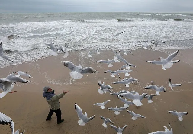 A man feeds seagulls on a beach in the Black Sea port of Yevpatoriya, Crimea on December 25, 2020. (Photo by Alexey Pavlishak/Reuters)