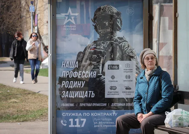 A woman waits at a bus stop next to a poster promoting Russian army service, as the Russia-Ukraine conflict continues, in Moscow, Russia on April 12, 2023. (Photo by Yulia Morozova/Reuters)