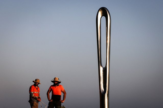 Two workers stand near a work titled “Vital Threads” by Brazilian artist Geraldo Zamproni that is part of the annual Sculpture by the Sea exhibition located near Bondi Beach in Sydney on October 16, 2025. (Photo by David Gray/AFP Photo)