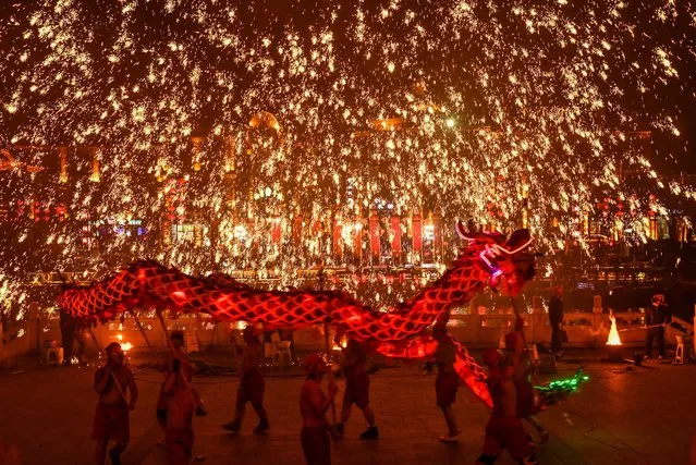 Folk artists perform dragon dance in the splash of molten iron at Tai'erzhuang Ancient Town during New Year's Eve celebrations on December 31, 2020 in Zaozhuang, Shandong Province of China. (Photo by Gao Qimin/VCG via Getty Images)