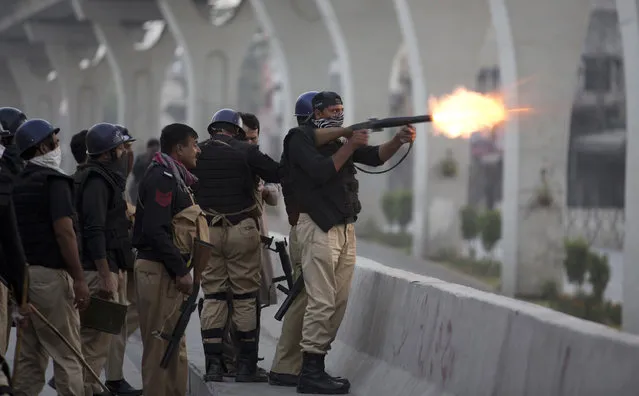 A Pakistani police officer fires tear gas shell to disperse crowd protesting against the government in Rawalpindi, Pakistan, Friday, October 28, 2016. Pakistani police have charged with batons and fired tear gas at stone-throwing supporters of cricketer-turned-politician Imran Khan who are rallying in Islamabad in defiance of a government-imposed ban on demonstrations. (Photo by B.K. Bangash/AP Photo)