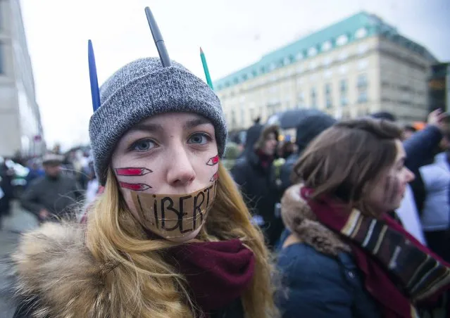 A woman wears a tape with the word “Liberte” (Freedom) on her mouth during a silent protest for the victims of the shooting at the Paris offices of weekly newspaper Charlie Hebdo, at the Pariser Platz square in Berlin January 11, 2015. (Photo by Hannibal Hanschke/Reuters)