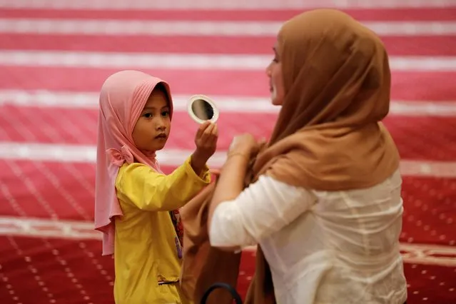 A Muslim girl holds a mirror while preparing for evening mass prayers known as “Tarawih” during the first eve of holy fasting month of Ramadan at the Great Mosque of Istiqlal in Jakarta, Indonesia on April 2, 2022. (Photo by Willy Kurniawan/Reuters)