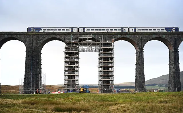 Workers erect scaffolding ahead of planned restoration work on the Ribblehead Viaduct, near Settle, northwest England on November 23, 2020. Restoration is underway on the Grade II listed Ribblehead Viaduct, which opened in 1875 and carries the Settle to Carlisle railway line. The works will re-point eroded mortar joints and replace broken stones on all 24 arches of the 1,318 ft (402m) long structure. (Photo by Paul Ellis/AFP Photo)