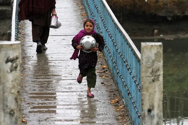 A girl with a bowl runs over a bridge after a rain on the outskirts of Peshawar January 22, 2015. (Photo by Fayaz Aziz/Reuters)