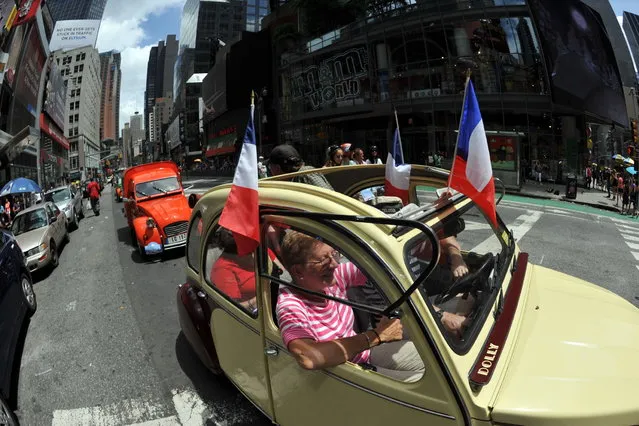 A parade of Citroen 2CV cars from the Greater New York Citroen and  Velosolex Touring Club passes through Time's Square on Bastille Day July 14, 2013 in New York. (Photo by Stan Honda/AFP Photo)