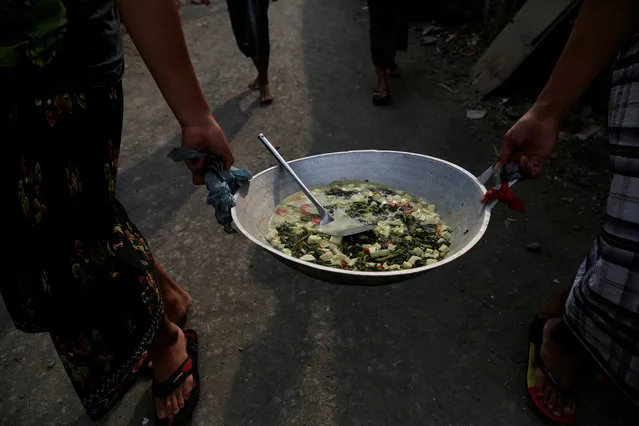 Students carry food they have cooked for iftar (breaking fast), during the holy month of Ramadan, at Lirboyo Islamic boarding school in Kediri, Indonesia, May 24, 2018. (Photo by Reuters/Beawiharta)