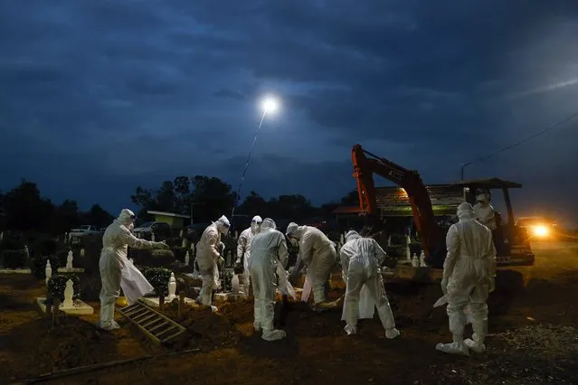 Workers in hazmat suits during a COVID-19 victims burial at Kuala Selangor, outside Kuala Lumpur, Malaysia, 25 January 2021. (Photo by Fazry Ismail/EPA/EFE)