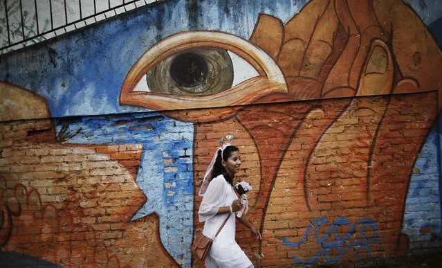 A reveller walks past a graffiti as she arrives at the annual carnival block party known as “Casas comigo” or “Marry me” at the Vila Madalena neighborhood  in Sao Paulo February 1, 2015. (Photo by Nacho Doce/Reuters)