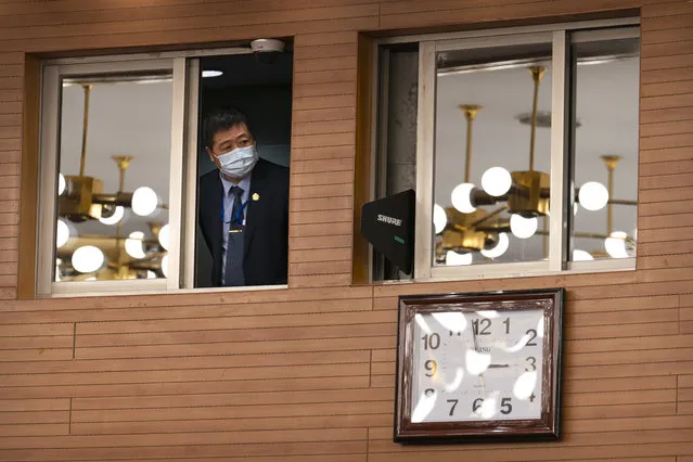 A staff member looks out from a control room before a remote video press conference by Chinese Foreign Minister Wang Yi held on the sidelines of the annual meeting of China's National People's Congress (NPC) in Beijing, Sunday, March 7, 2021. (Photo by Mark Schiefelbein/AP Photo)