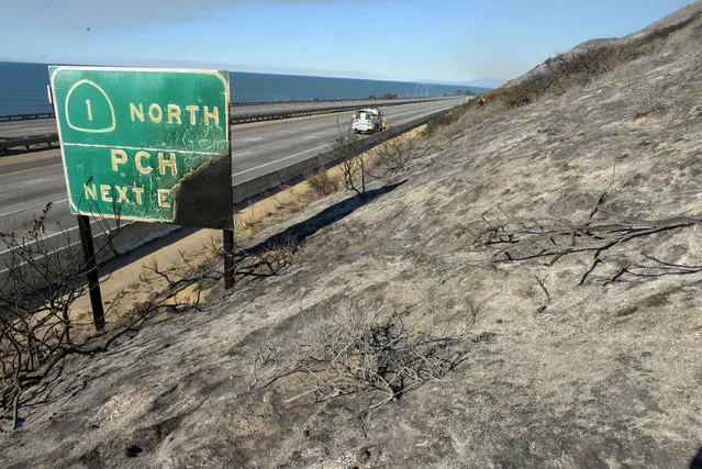 Parked on a closed US Highway 101, a Santa Barbara County Fire Department fire engine and crew douse a hot spot while working a Solimar wildfire in Ventura County, Calif. on  Saturday, December 26, 2015. The fire, which began on Christmas night, has charred 1,200 acres. (Photo by Mike Eliason/Santa Barbara County Fire Dept. via AP Photo)