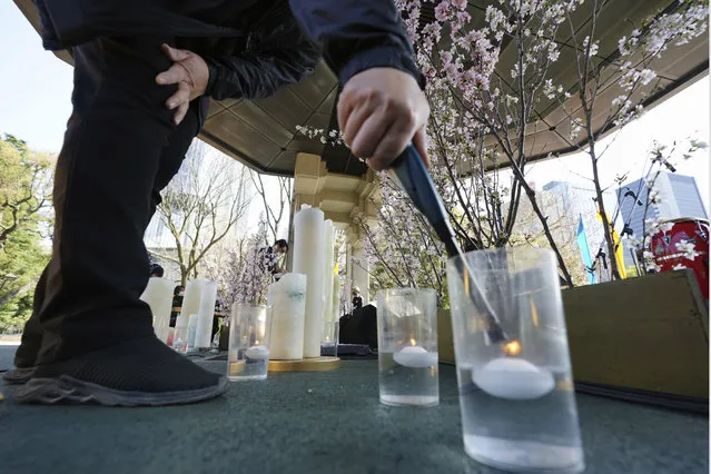 A staff member prepares the decoration to mourn for the victims of the 2011 earthquake and tsunami prior to an online special memorial event at Hibiya Park in Tokyo Thursday, March 11, 2021. (Photo by Eugene Hoshiko/AP Photo)