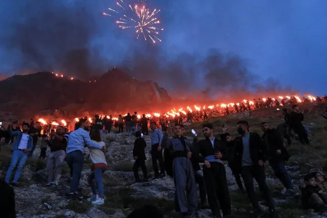 Iraqi Kurdish people carry fire torches, as they celebrate Nowruz Day, a festival marking the first day of spring and the new year, in the town of Akra near Duhok, in Iraqi Kurdistan, Iraq on March 20, 2021. (Photo by Ari Jalal/Reuters)