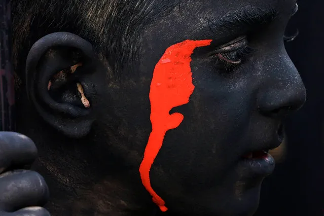 A boy has his body painted in black and red to portray a demon as he prepares to join an annual religious performance of Taazieh in Noosh Abad, on July 26, 2023, during the Muslim month of Muharram in the lead-up to Ashura commemorating the seventh-century killing of Prophet Mohammed's grandson Imam Hussein. (Photo by Atta Kenare/AFP Photo)