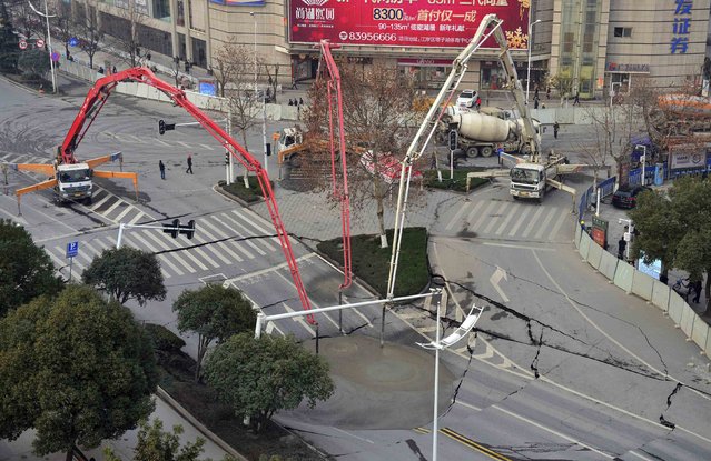 Workers use cement to fill in part of a road that caved in, in Wuhan, Hubei province February 11, 2015. No one was injured when the area of around 300 square metres (3229 square feet) caved in on Tuesday evening due to a fault in the construction of a subway line, local media reported. (Photo by Reuters/China Daily)