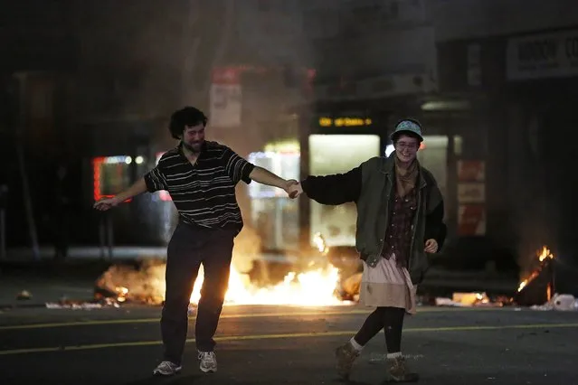 Demonstrators dance in front of trash fire during a march against the New York City grand jury decision to not indict in the death of Eric Garner in Berkeley, California December 8, 2014. A New York City grand jury decision not to charge white police officer Daniel Pantaleo who killed Garner, an unarmed black man, with a chokehold sparked outrage and protests on Wednesday, and the U.S. Justice Department said it would investigate the incident. (Photo by Stephen Lam/Reuters)